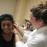 Pacific School of Oriental Medicine student Casey Culp works with Azeba Ghebrewold after treating her with acupuncture during The Pacific Beach Free Clinic, put on by the Pacific School of Oriental Medicine, at the Pacific Beach United Methodist Church in Pacific Beach on Wednesday. Hayne Palmour IV/San Diego Union-Tribune