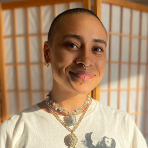 A headshot of a person in front of a wooden/paper screen.