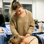 Acupuncture students practicing hands-on treatment techniques in a classroom