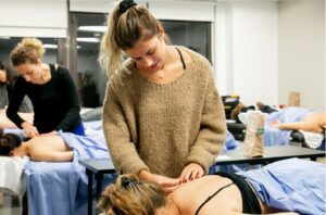 Acupuncture students practicing hands-on treatment techniques in a classroom