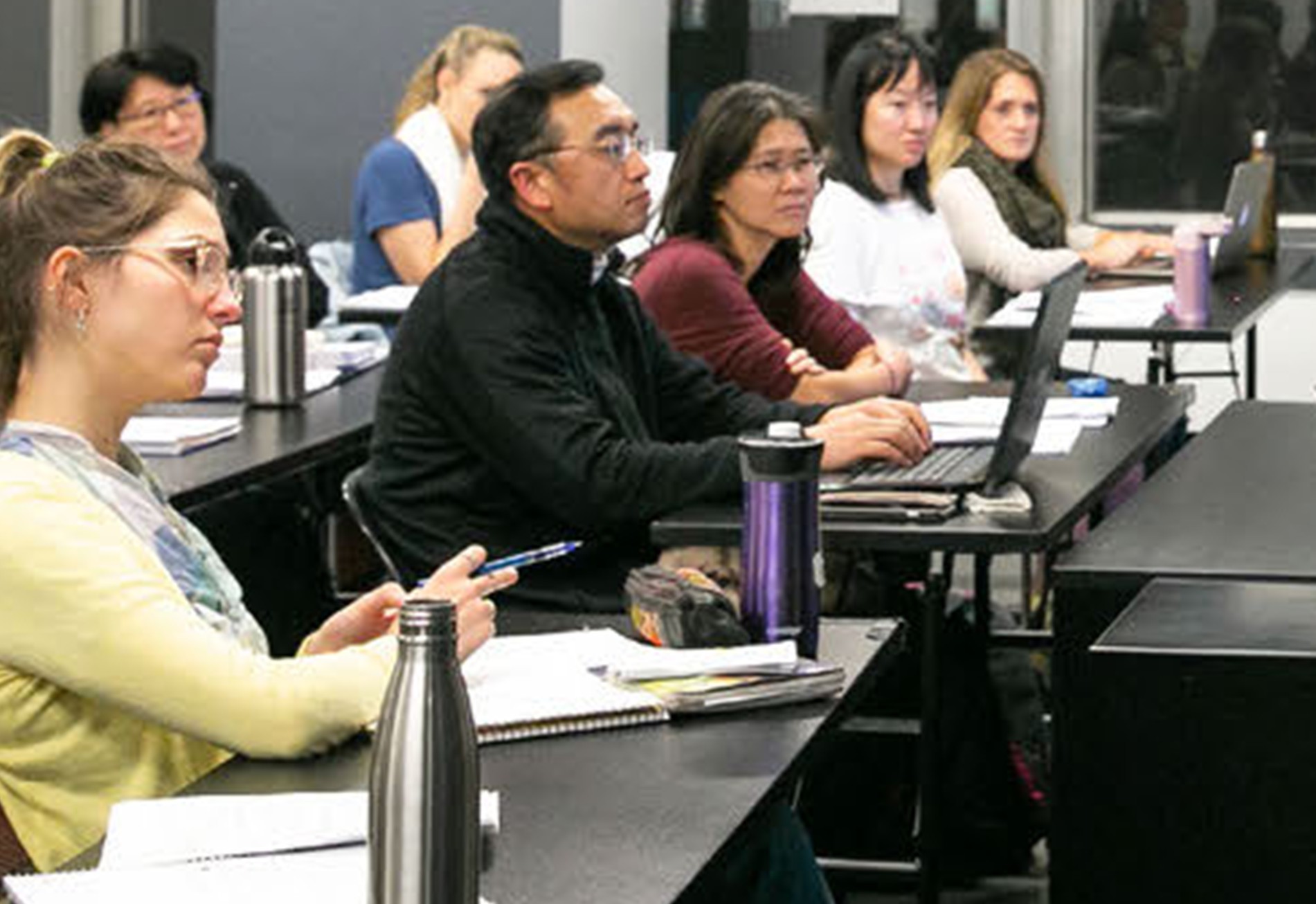 Acupuncture students studying Eastern medicine theory and anatomy in classroom setting
