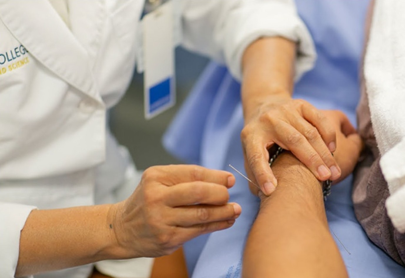 Acupuncture student performing hands-on clinical training with patient in treatment setting
